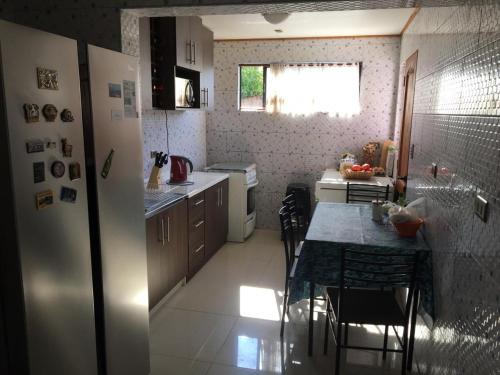 a small kitchen with a table and a refrigerator at HOSTAL CAUQUENES in De Cauquenes