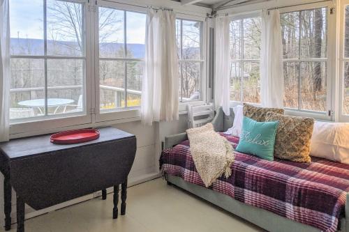 a bedroom with windows and a bed and a table at Cozy Stockbridge Cabin - Walk to Beach and Lake! in Stockbridge