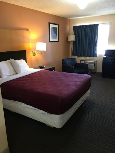 a hotel room with a large bed and a chair at Rodeway Inn Sergeant Bluff - Sioux City in Sergeant Bluff