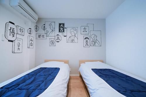 two beds in a room with drawings on the wall at Kamon Inn Toji Higashi in Kyoto