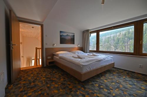 a bedroom with a bed and a large window at Vetrnik Depandance Hotelu Jirinka in Dolní Morava