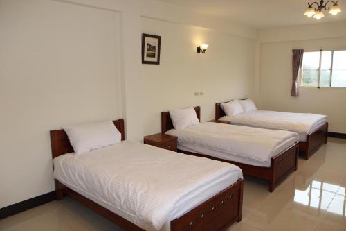 two beds in a room with white sheets at Dapu Inn in Juguang