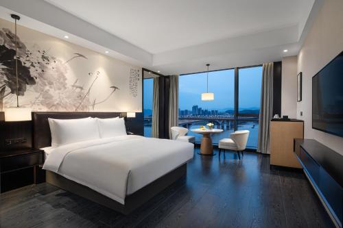 a bedroom with a large white bed and a large window at Yiho Hotel Mawei Fuzhou in Fuzhou