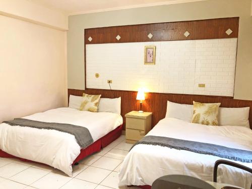 a hotel room with two beds and a lamp at Yun’s Homestay in Luodong