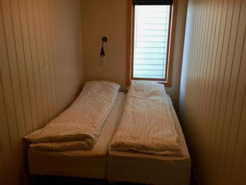 2 Betten in einem kleinen Zimmer mit Fenster in der Unterkunft Nabben Inn in Selje