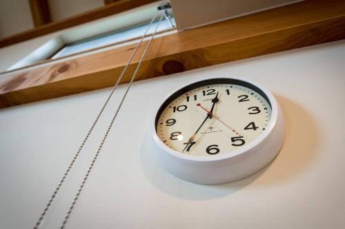 a clock hanging on a wall next to a window at TOOD一宮 -B棟 in Ichinomiya
