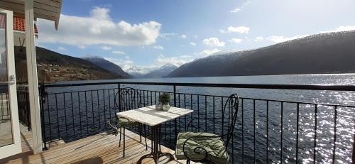 a table and chairs on a balcony with a view of a lake at Fjord Paradise Stryn in Stryn