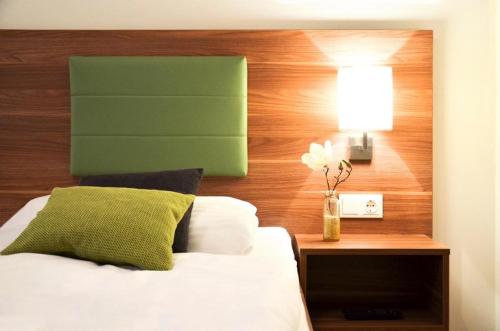 Frühstückspension Reinhard Todt في تزفيتل: غرفة نوم بها سرير مع اللوح الأمامي الأخضر ومصباح