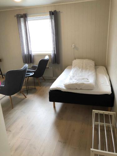 a bedroom with a bed and chairs and a table at Mosjøen Overnatting, Vollanvegen 13 in Mosjøen