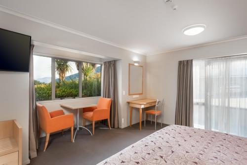 a hotel room with a bed and a table and chairs at Queenstown Motel Apartments in Queenstown
