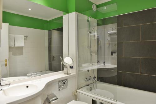 a bathroom with a sink and a shower and a tub at Michel Hotel Wetzlar in Wetzlar