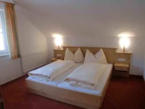 a bedroom with a large bed with white sheets and pillows at Pension Gondelstube in Schladming