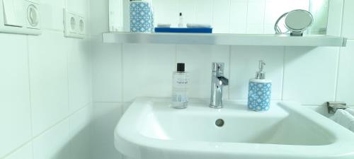 een witte wastafel in een badkamer met een spiegel bij B&B Le Bon Vivant Eindhoven in Eindhoven