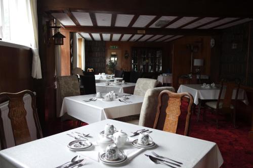 un restaurante con mesas blancas y sillas con cubiertos en Gable End Hotel, en Great Yarmouth
