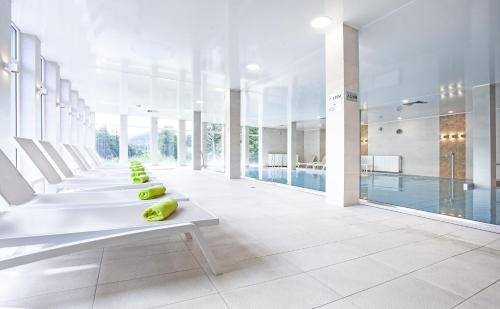a room with a pool and a row of white chairs at Holimo Hotel in Stronie Śląskie