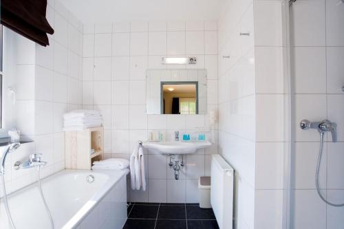 a white bathroom with a tub and a sink at Chalet Alpinresort - JOKERCARD INCLUDED in Saalbach Hinterglemm