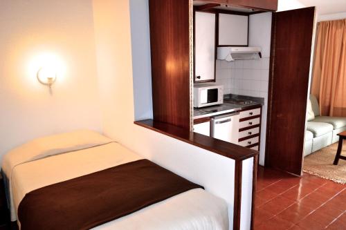 Kleines Zimmer mit einem Bett und einer Mikrowelle. in der Unterkunft Vilas Maria in Funchal