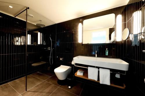 a bathroom with a large mirror and a bath tub at Best Western Plus Hotel Bern in Bern