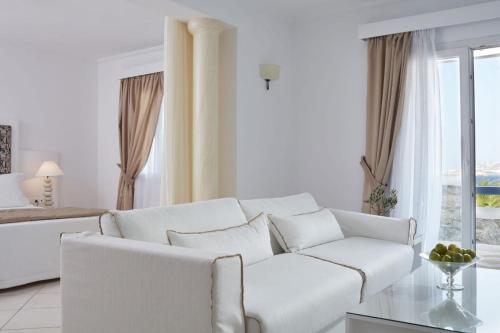 a white living room with a white couch and a table at Grand Beach Hotel in Mýkonos City