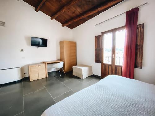 a bedroom with a bed and a desk and a window at Giardino Sul Duomo in Ragusa