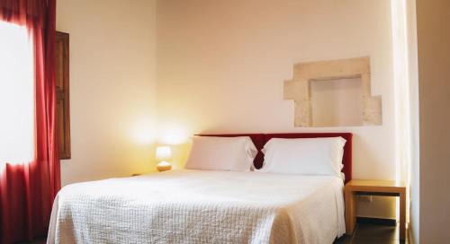a bedroom with a bed with white sheets and a mirror at Giardino Sul Duomo in Ragusa