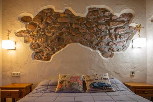 a bedroom with a stone wall with a bed and two tables at Posada Elbete in Elbete