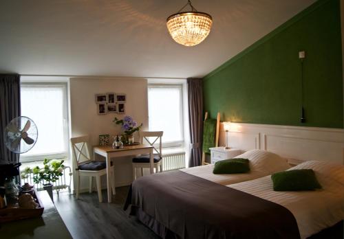 ein Schlafzimmer mit einer grünen Wand, einem Bett und einem Schreibtisch in der Unterkunft The Studio Guesthouse in Volendam