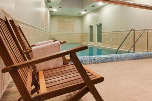 una silla de madera sentada frente a una piscina en Spa hotel Čajkovskij, en Karlovy Vary