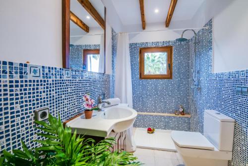 Ideal Property Mallorca - Can Tomeu في يوبي: حمام من البلاط الأزرق مع حوض ومرحاض