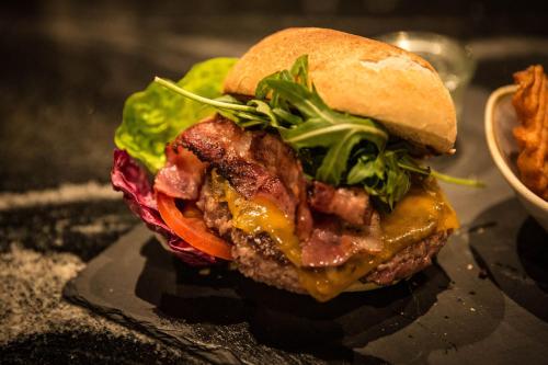 a sandwich with bacon cheese and lettuce on a plate at Parkhotel Schmid in Adelsried