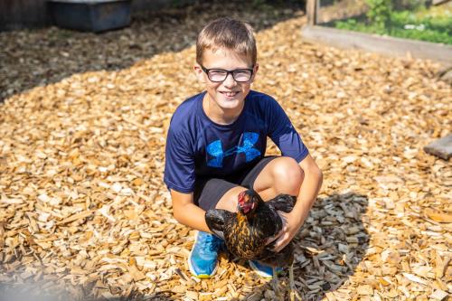 a young boy is holding a chicken in a yard at Landhaus Fingerhof in Flachau