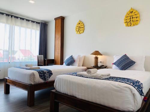 a hotel room with two beds and a window at C Hotel Boutique and Comfort in Chiang Mai