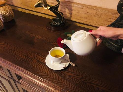 a woman is holding a cup of tea on a table at Карпаты in Khust