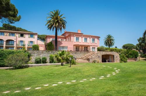 a large pink house with palm trees in the yard at Hôtel Les Jardins De Sainte-Maxime in Sainte-Maxime