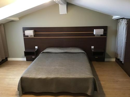 a bedroom with a bed with a brown headboard at Hotel Restaurant Elissaldia in Bidart