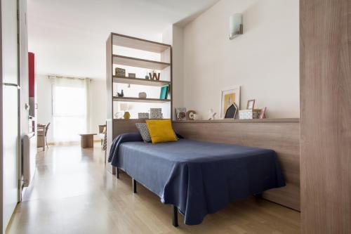 Dormitorio con cama con almohada amarilla en Alojamientos Universitarios Hipatia, en Terrassa