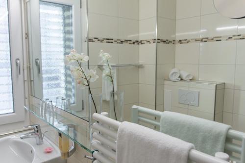 un baño con lavabo y un jarrón con flores. en Hotel SiX, en Kreuzlingen