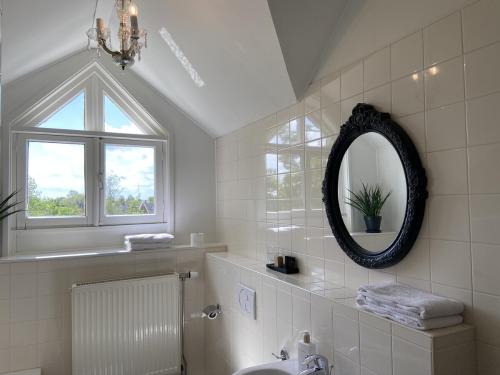 a white bathroom with a mirror and a sink at De Os en het Paard in Deil