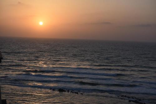 a sunset over the ocean with the sun setting at Penthouse Apartment On The Beach in Bat Yam
