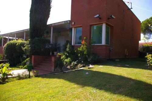 a red brick house with a tree in the yard at B&B Inés in Sant Cugat del Vallès