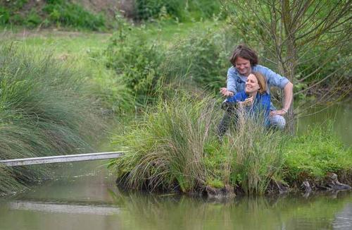 a man and woman standing next to a body of water at Holiday home on farm (La Ferme du Tao) in Beaugies-sous-Bois