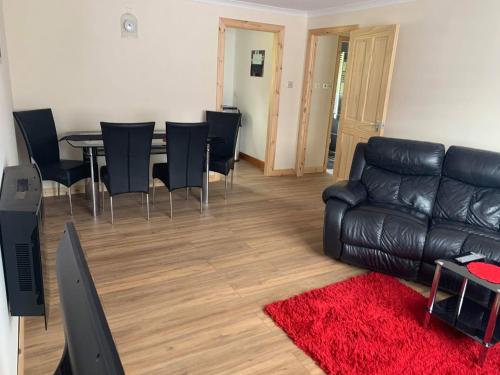 a living room with a black leather couch and a table at Flat 18 in Dumfries