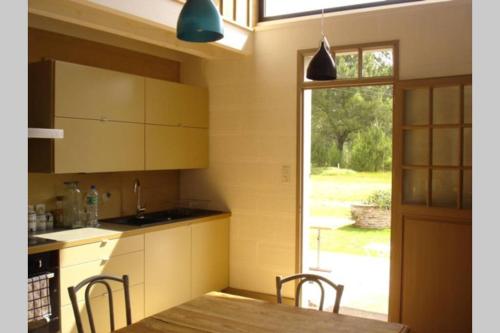 une cuisine avec une table et des chaises et une fenêtre dans l'établissement Maison-loft rénovée design 4 étoiles luxe - Vaste parc - à 7 min des plages et golfs, à Messanges