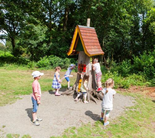 un groupe d'enfants debout autour d'une maison de jeu en bois dans l'établissement Self Catering - The Garden House, à Wexford