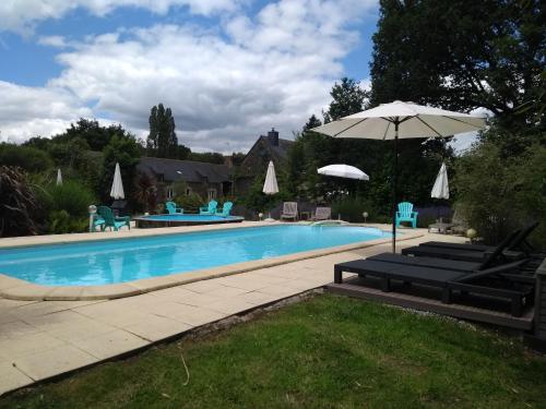 a swimming pool with an umbrella and chairs at Gites De Lenvos in Pontivy