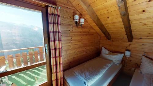 Cama pequeña en habitación de madera con ventana en Tschuggen 75, en Blatten bei Naters