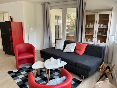 a living room with a black couch and red chairs at Eifelblümchen in Heimbach