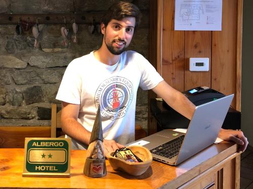 a man sitting at a table with a laptop computer at Chalet Saint-Barthélemy Hotel in Nus