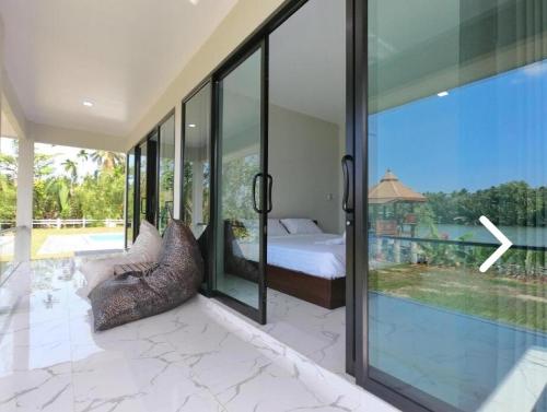 a bedroom with a bed and a large glass window at Suan Son Villa Koh Sa Nher สวนสนธิ์วิลล่า เกาะเสนอ SHA in Surat Thani