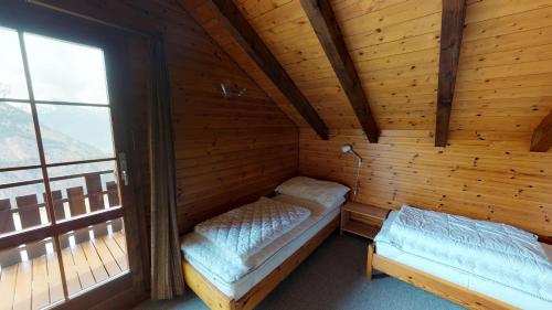 a room with two beds in a wooden cabin at Tschuggen 61 in Blatten bei Naters